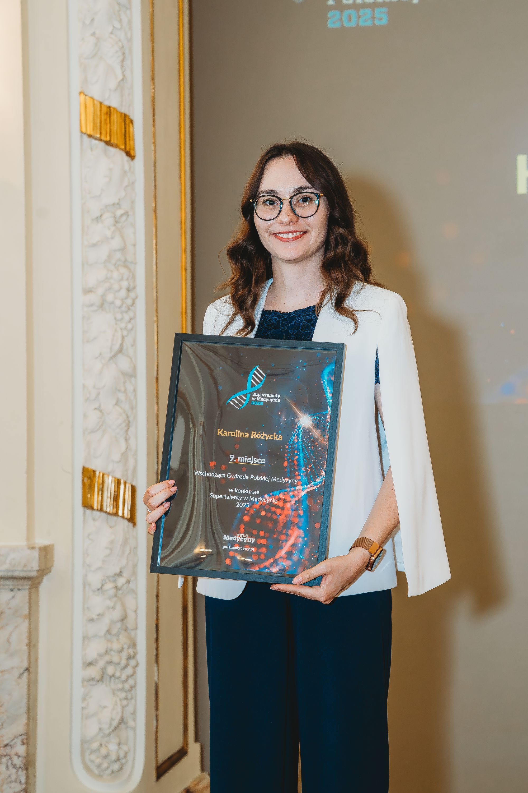 Zdjęcie przedstawia studentkę - brunetkę, pozującą do zdjęcia.
