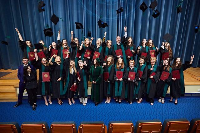 studeni pozują do zdjęcia grupowego i podrzucają swoje birety do góry