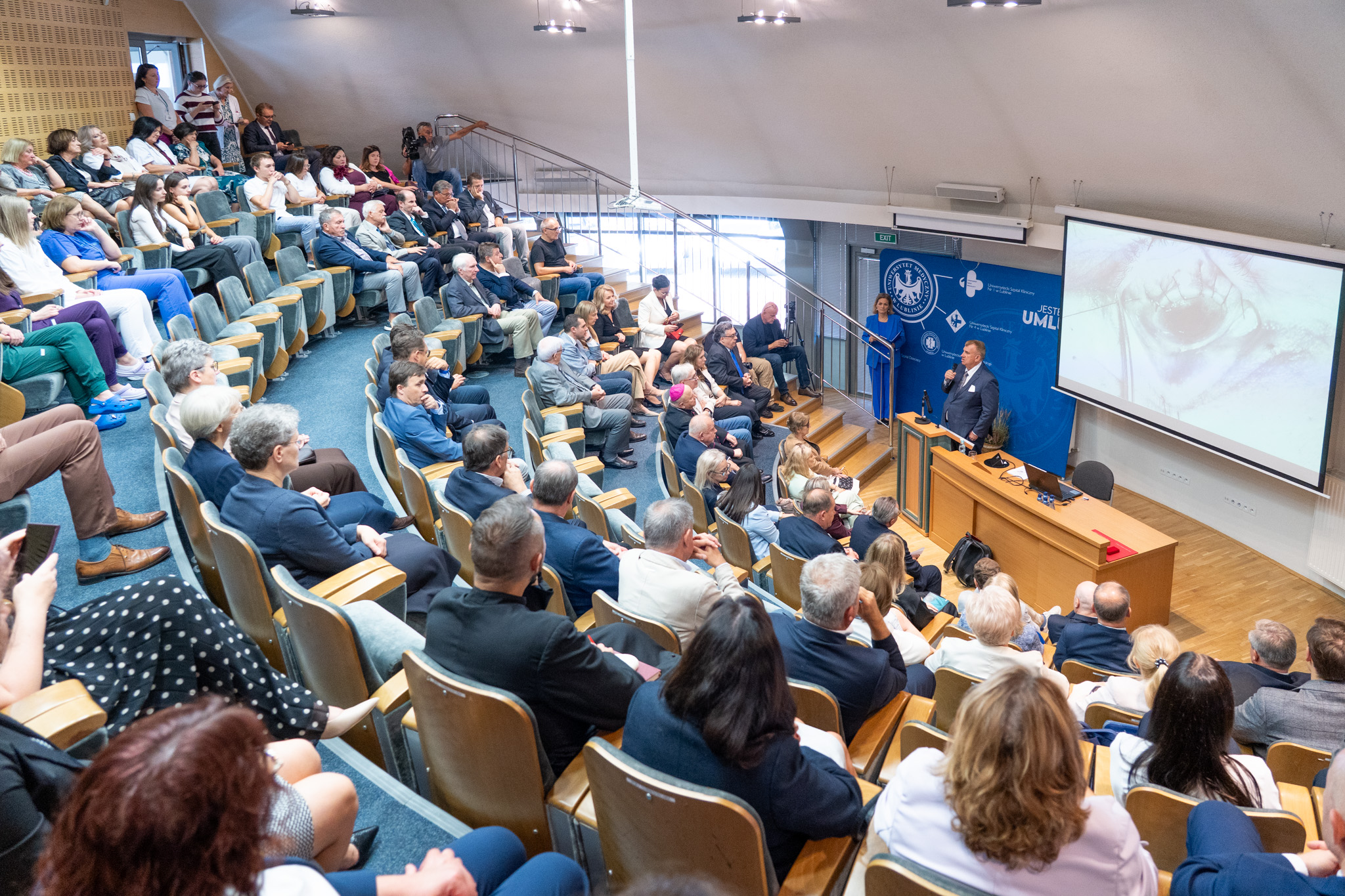 zdjęcie uczestników wydarzenia na auli, przemawia rektor 