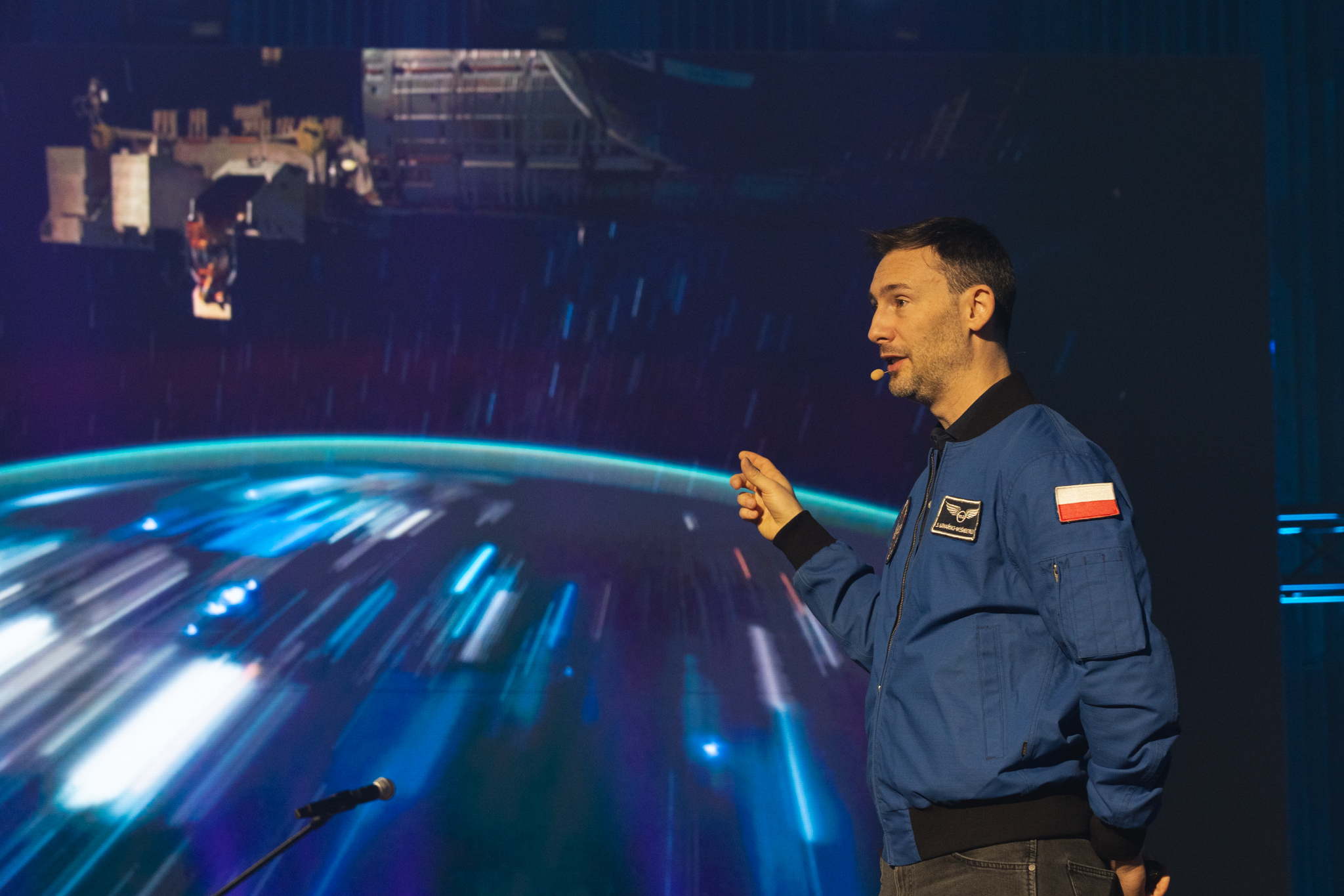 S.Uznański-Wiśniewski na tle fotografii ziemi zrobionej zz kosmosu