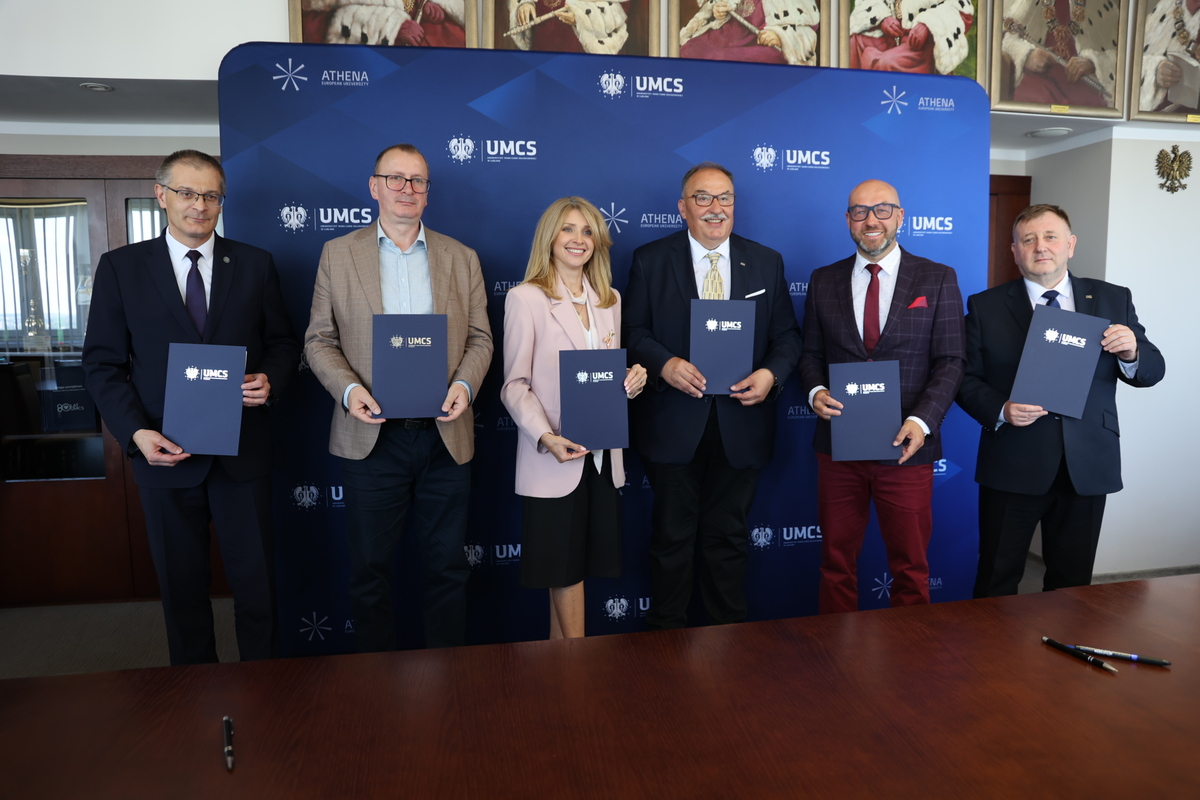 prorektorzy pozują na ściance uczelni